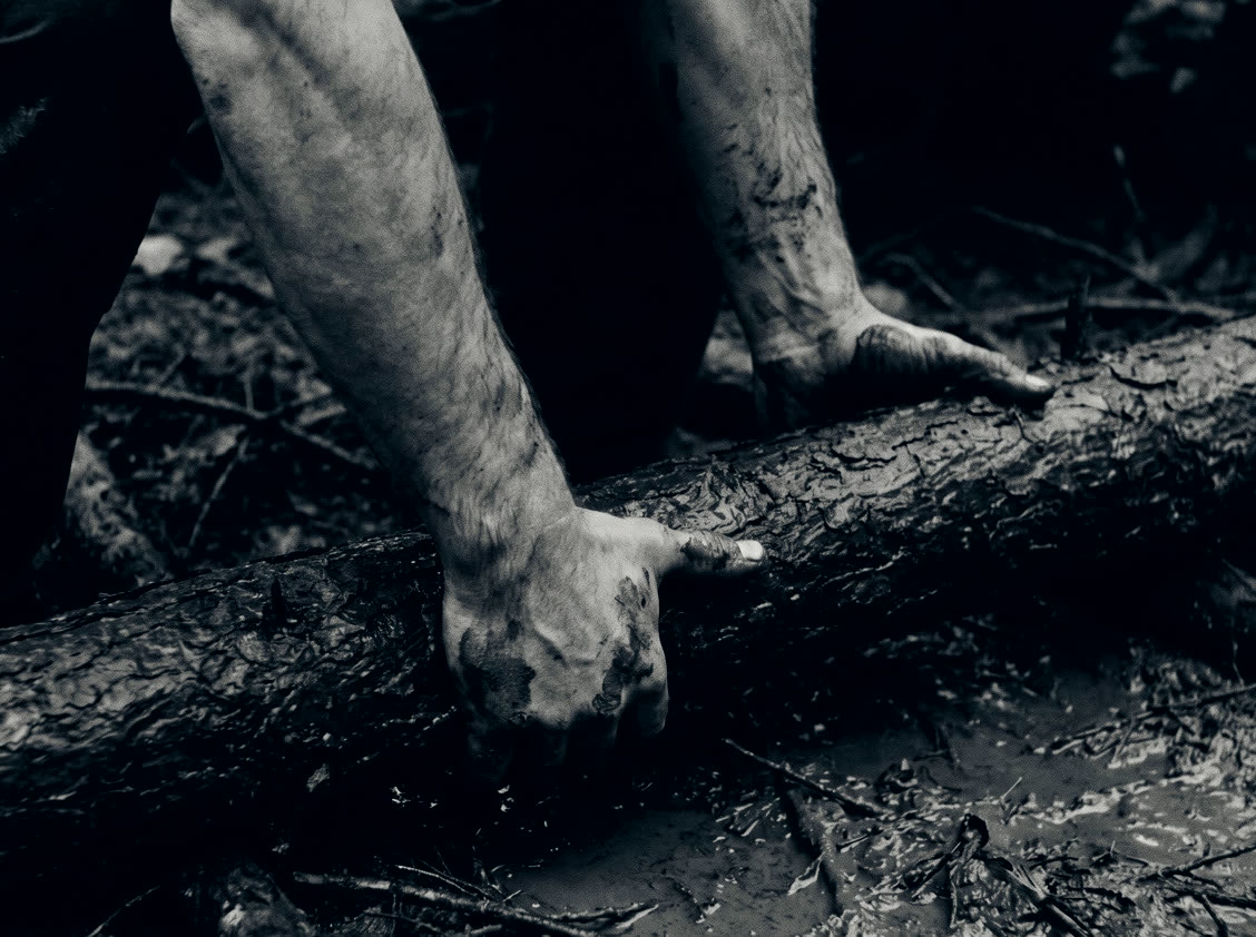 Hands on a mud-slicked log.