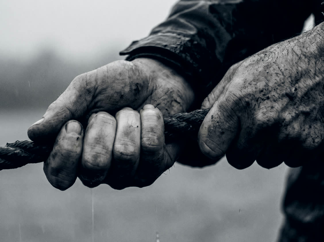 Raw hands gripping a wet rope, knuckles white.